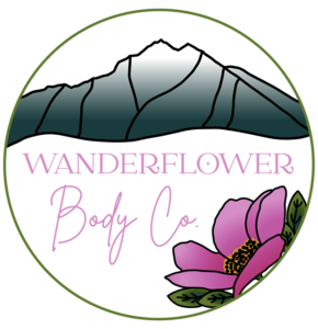 Wanderflower Body Co. in pink inside circle logo with Pioneer Peak and pink arctic rose.